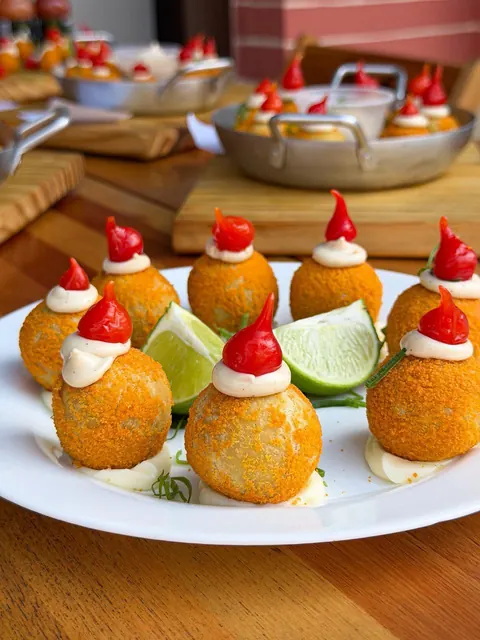 Bolinhos servidos com molho, pimentas e limão